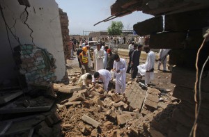 Security officials survey the site of a bomb explosion at a police check post in Peshawar