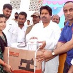 Minister for Housing Raman Bhalla distributing sewing machine to a woman on Sunday.