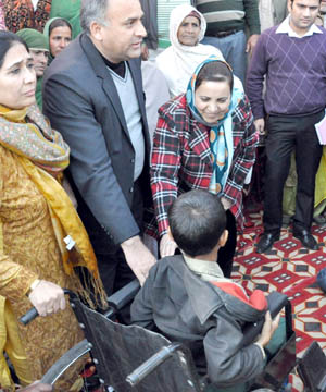 Minister for Social Welfare Sakina Itoo and MoS Health Shabir Ahmad Khan distributing wheel chair to a handicapped child at Jammu on Friday.