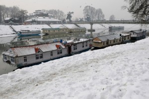 Moderate snow accumulated on the banks of river Jhelum and roofs of house boats in Srinagar on Monday. -Excelsior/Amin War
