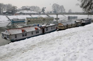 Moderate snow accumulated on the banks of river Jhelum and roofs of house boats in Srinagar on Monday.  -Excelsior/Amin War