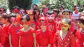 Students of Apple Kids International School wearing red dresses while posing for a group photograph during Red Day celebration.