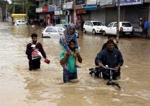 A man evacuates an elderly woman to a higher ground at a flooded road in Srinagar on Sunday.(UNI)