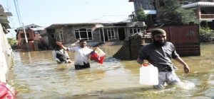 People walk through the flood water to safer place at Batmaloo residential area of Srinagar on Wednesday. More pics on page Nos 3 & 7.-Excelsior/ Amin War