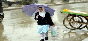 A woman takes cover of umbrella as rains lashed Anantnag on Tuesday. -Excelsior/Sajad Dar