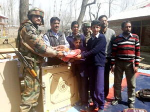 Army person handing over sports items to students at Pampore on Monday.