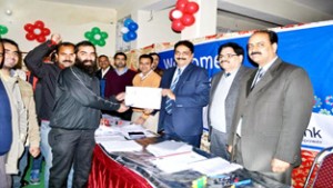 J&K Bank officials handing over first Shri Amarnath Yatra slip to Ujwal Sharma at Jammu on Monday.
