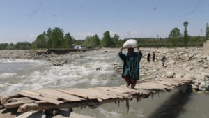 People using make shift bridge to cross Rohmsi Nullah at Rahmoo in Pulwama on Wednesday. — Excelsior/ Youhis Khaliq