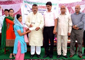Minister for Industries, Chander Parkash handing over a cheque to a beneficiary at Chenani on Monday.