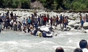 Policemen and people pulling wreckage of car from river after it rolled down from road near Mandi on Sunday.