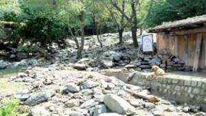 Road filled with boulders and mud following flash floods in Latti.