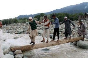People cross Ranbi Ara on wooden log in absence of bridge at Heerpora in South Kashmir’s Shopian district.  — Excelsior/Younis Khaliq