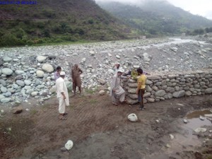 People of Kulani village in tehsil Mandi of Poonch District raising a crate to prevent the village from floods.