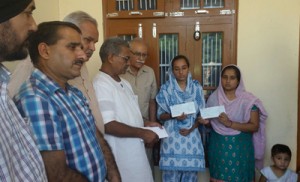 RSS leader handing over relief cheques to victims of border firing at R S Pura on Friday.