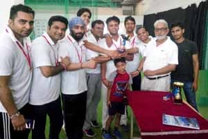 Chief guest, Dr Ram Thakur, Director of KC Public School presenting trophy to winners of 2nd Inter Telecom Indoor Cricket Tournament at KCSC in Jammu on Sunday.