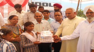 MLA Suchetgarh Sham Choudhary distributing school bags among students on Thursday.