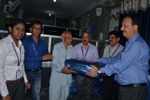 A senior SBI officer presenting blanket during a medical camp at SBI Garhi in Jammu.