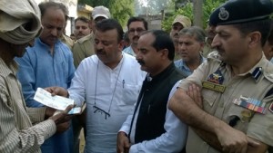Minister for Industries, Chander Prakash Ganga handing over relief cheque during his visit to firing affected village.