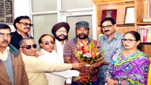 Artists presenting a bouquet to Dr Aziz Hajni, Secretary, J&K Academy of Art, Culture and Languages at Jammu on Tuesday.
