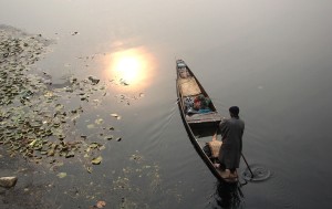 A fisherman rows his boat on Dal lake as temperature shows improvement in Srinagar on Sunday. — Excelsior/Shakeel