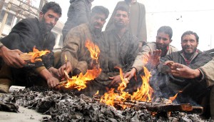People warming themselves with fire as cold grips Srinagar on Saturday. -Excelsior/Shakeel
