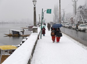 Students walk amid snowfall along Boulevard in Dalgate area of Srinagar on Wednesday. —Excelsior/Shakeel