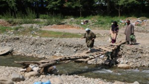 An old woman struggles to walk over a rickety bridge at South Kashmir's Tral area. — Excelsior/ Younis Khaliq