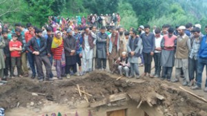 Villagers gathered near a mud house, portion of which collapsed in village Upper Tanta in Doda district.