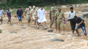 MLA Ranbir Singh Pathania crossing a nallah to assess the post flood situation in a village in Ramnagar. 