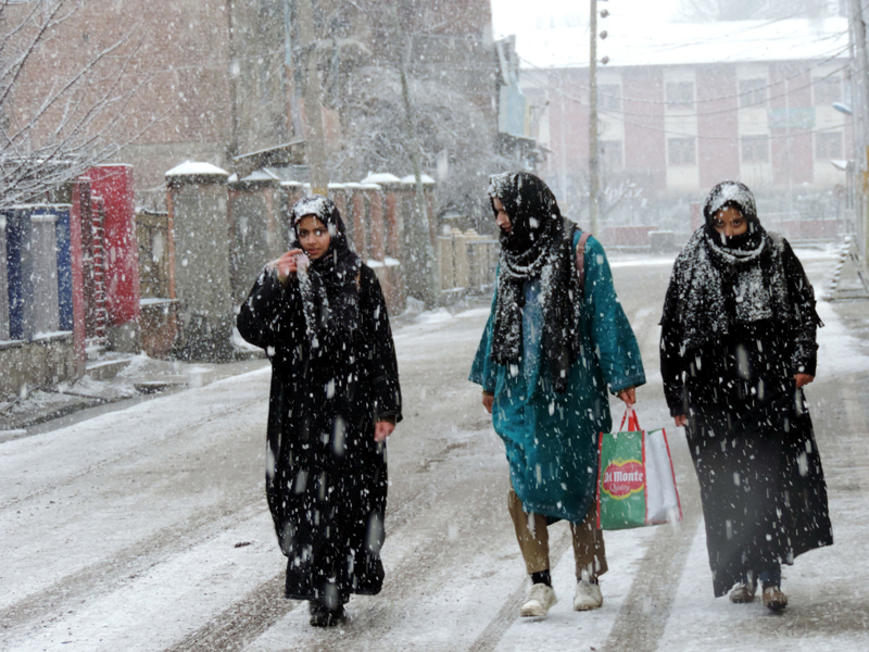 Women walking down a street amid snowfall in Srinagar on Thursday. (UNI)