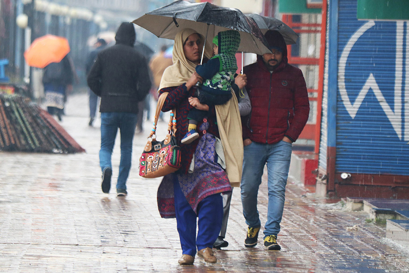 Woman takes umbrella cover during rain in Srinagar on Friday. -Excelsior/ Shakeel
