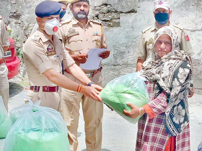 SHO Ramsoo DySP (Prob) Dr Sumit Sharma distributing dry ration to a needy lady.-Excelsior/Parvaiz