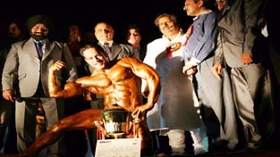 Body Builder displaying muscles while receiving a glittering trophy from the chief guest, Raman Bhalla, Minister for Sports in Jammu on Saturday. -Excelsior/Rakesh Body Builder displaying muscles while receiving a glittering trophy from the chief guest, Raman Bhalla, Minister for Sports in Jammu on Saturday. -Excelsior/Rakesh