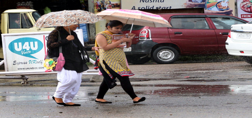Girls hold umbrella to protect themselves from rain in Jammu on Sunday. (UNI)