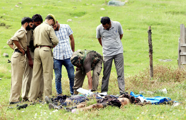 People and police man stand near the bodies of three unidentified militants killed in an encounter at Zachaldara in Handwara on Sunday. Excelsior/Aabid Nabi
