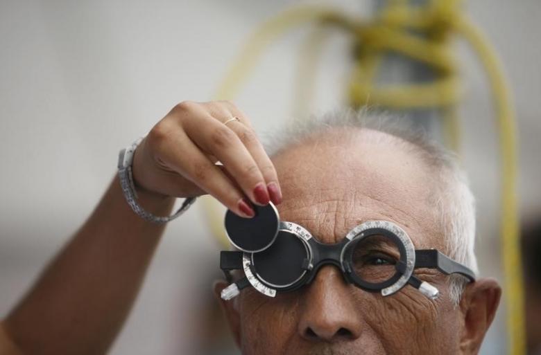 A man receives an eye exam as an ophthalmologist changes a lens during a health campaign in the suburb of Escobedo