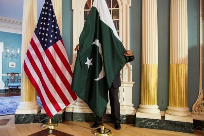 A State Department contractor adjust a flag before a meeting between U.S. Secretary of State Kerry and Pakistan's Interior Minister Khan on the sidelines of the White House Summit on Countering Violent Extremism at the State Department in Washington