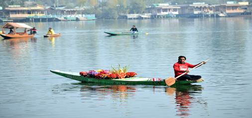A boy rows a boat carrying flowers to sell on Dal lake in Srinagar. -Excelsior/Shakeel