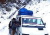 A vehicle being pulled out of fresh snowfall by passengers on Mughal Road near Poshana in Surankote on Tuesday. -Excelsior/ Ramesh Bali