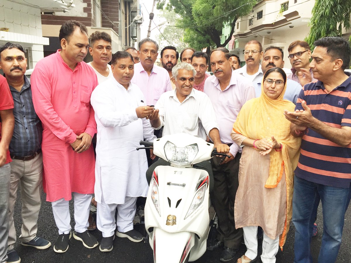 Ex MLA Sat Sharma handing over key of scooty to a differently abled person. Ex MLA Sat Sharma handing over key of scooty to a differently abled person.