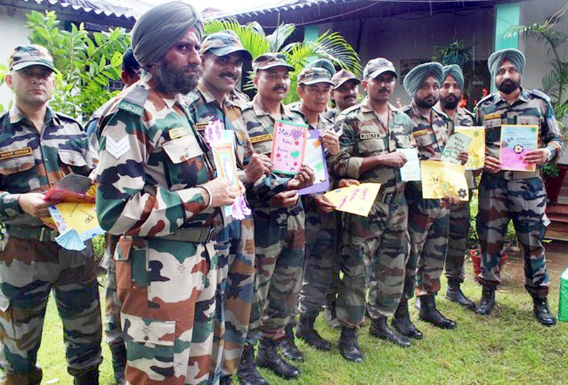 Army personnel posing with Raksha Bandhan greeting cards presented by school children. Army personnel posing with Raksha Bandhan greeting cards presented by school children.