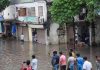 People look on at a waterlogged street where floodwater spilled out of the drainage line following heavy monsoon rainfall, in Surat on Saturday.