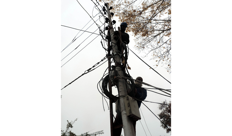 Employees of Power Development Department rectify the fault on top of an electric pole in Srinagar. (UNI) Employees of Power Development Department rectify the fault on top of an electric pole in Srinagar. (UNI)