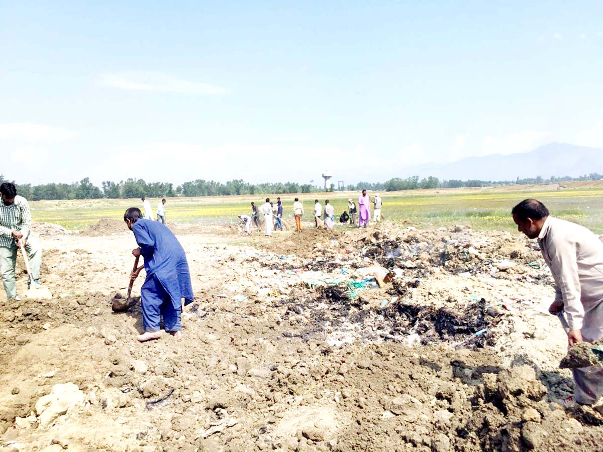 Labourers engaged in earth-filling work at garbage dumping site near Wullar wetland in Sopore. Labourers engaged in earth-filling work at garbage dumping site near Wullar wetland in Sopore.