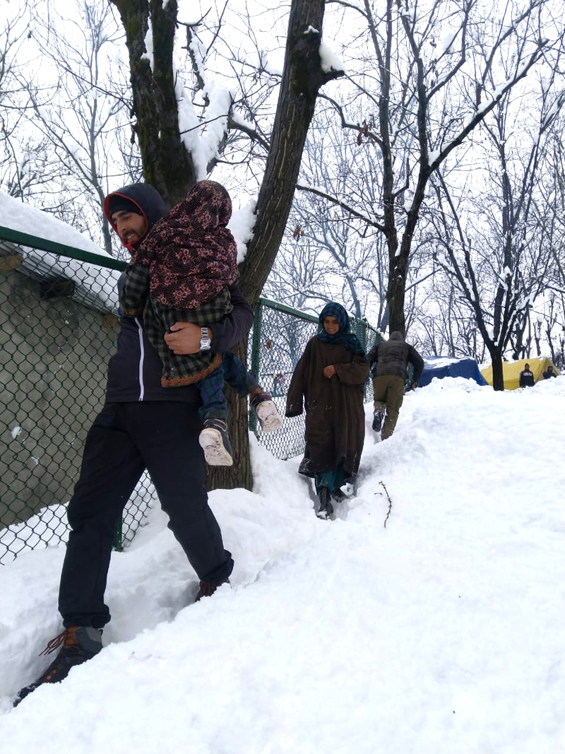 A police official rescuing Bakerwal family stuck in snow at higher reaches of Devsar in Kulgam. A police official rescuing Bakerwal family stuck in snow at higher reaches of Devsar in Kulgam.