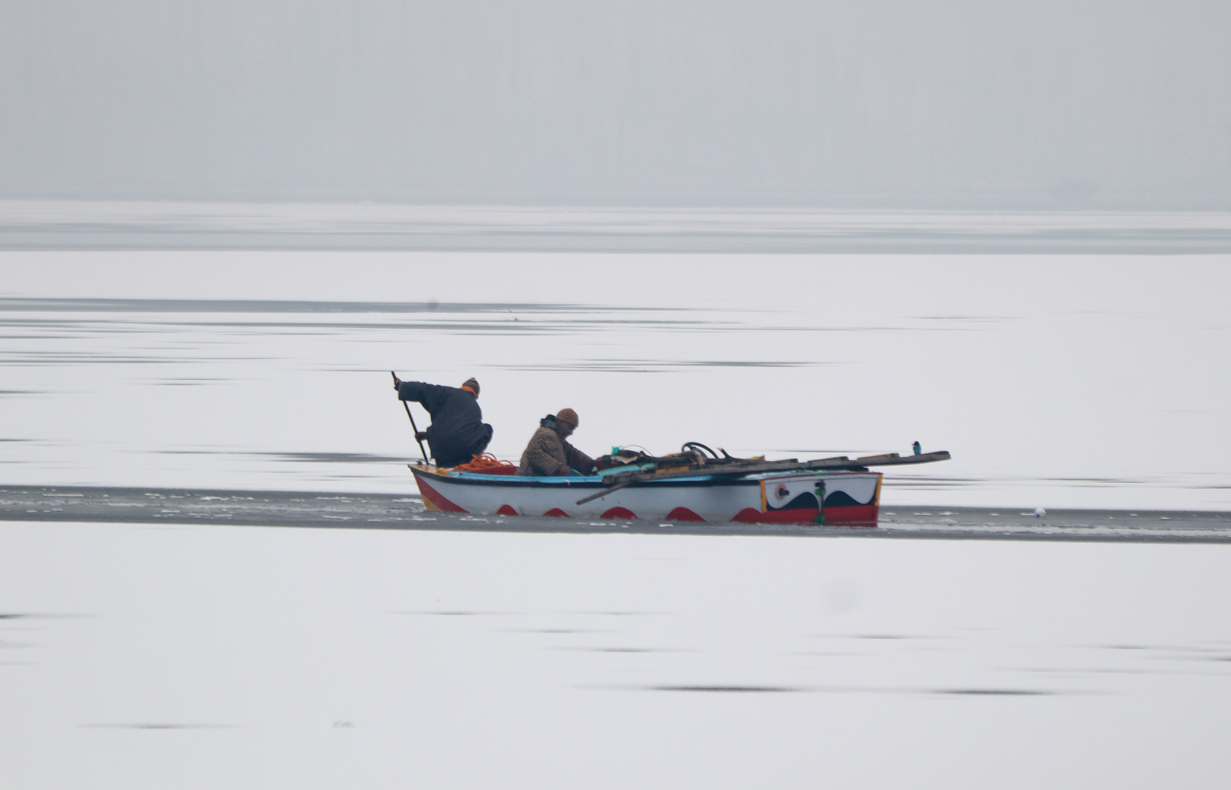 Men on a motorboat in frozen Dal Lake in Srinagar.Excelsior/Shakeel