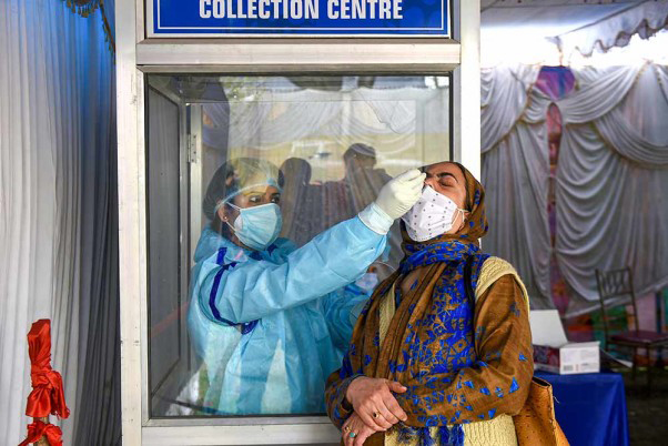 A health worker conducts COVID-19 testing of a woman, amid a countrywide spike in coronavirus cases, in Srinagar.