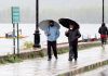People take cover under umbrellas as they walk in Srinagar on Thursday. — Excelsior/Shakeel