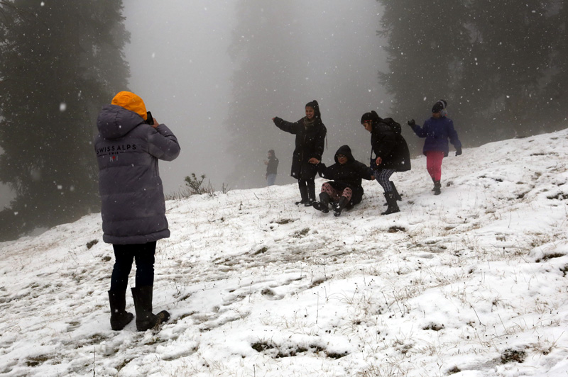 Tourists walk on snow covered Gulmarg on Sunday. -Excelsior/Aabid Nabi Tourists walk on snow covered Gulmarg on Sunday. -Excelsior/Aabid Nabi