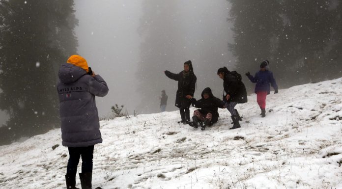 Tourists walk on snow covered Gulmarg on Sunday. -Excelsior/Aabid Nabi